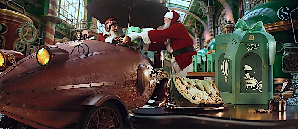 Papai Noel entrega presente em oficina mágica com panetone.