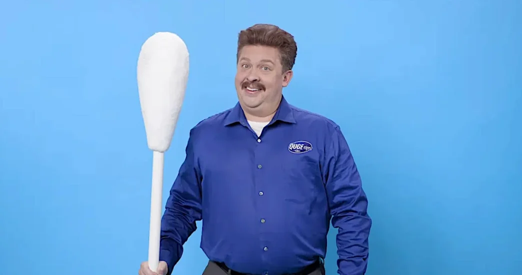 Homem sorridente com cotonete gigante.