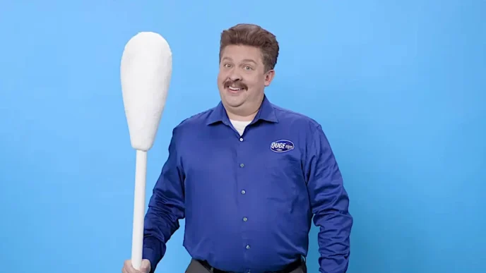 Homem sorridente com cotonete gigante.