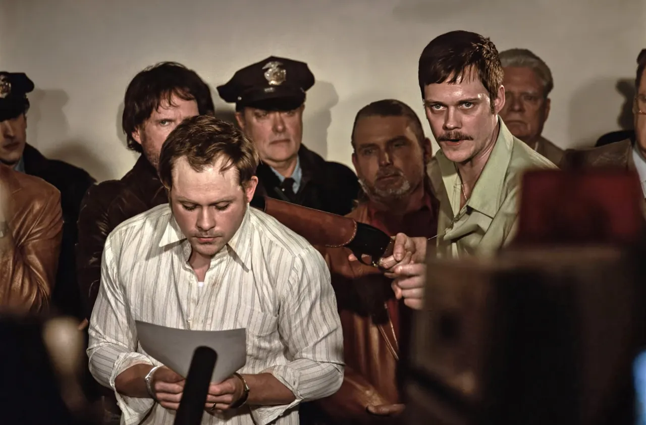 Homens tensos com policial em cena dramática.