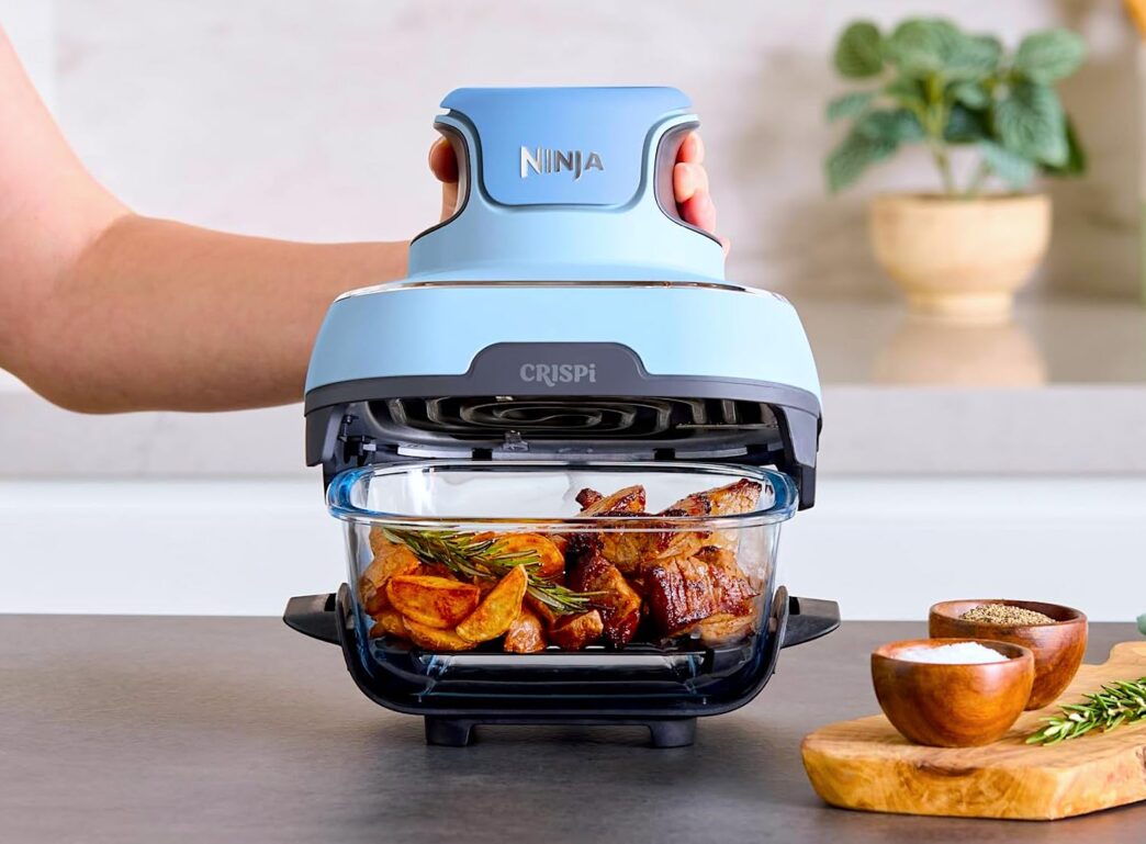 Airfryer preparando carne e batatas na cozinha.