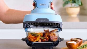 Airfryer preparando carne e batatas na cozinha.
