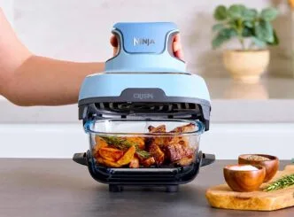 Airfryer preparando carne e batatas na cozinha.