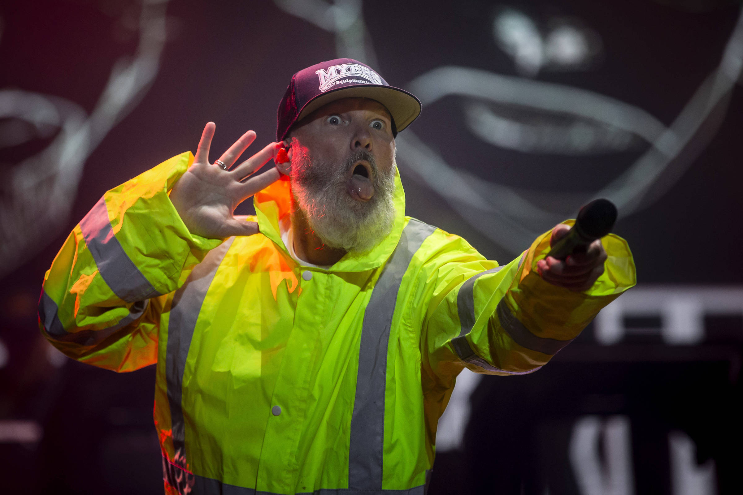 Cantor de jaqueta amarela no palco, microfone na mão