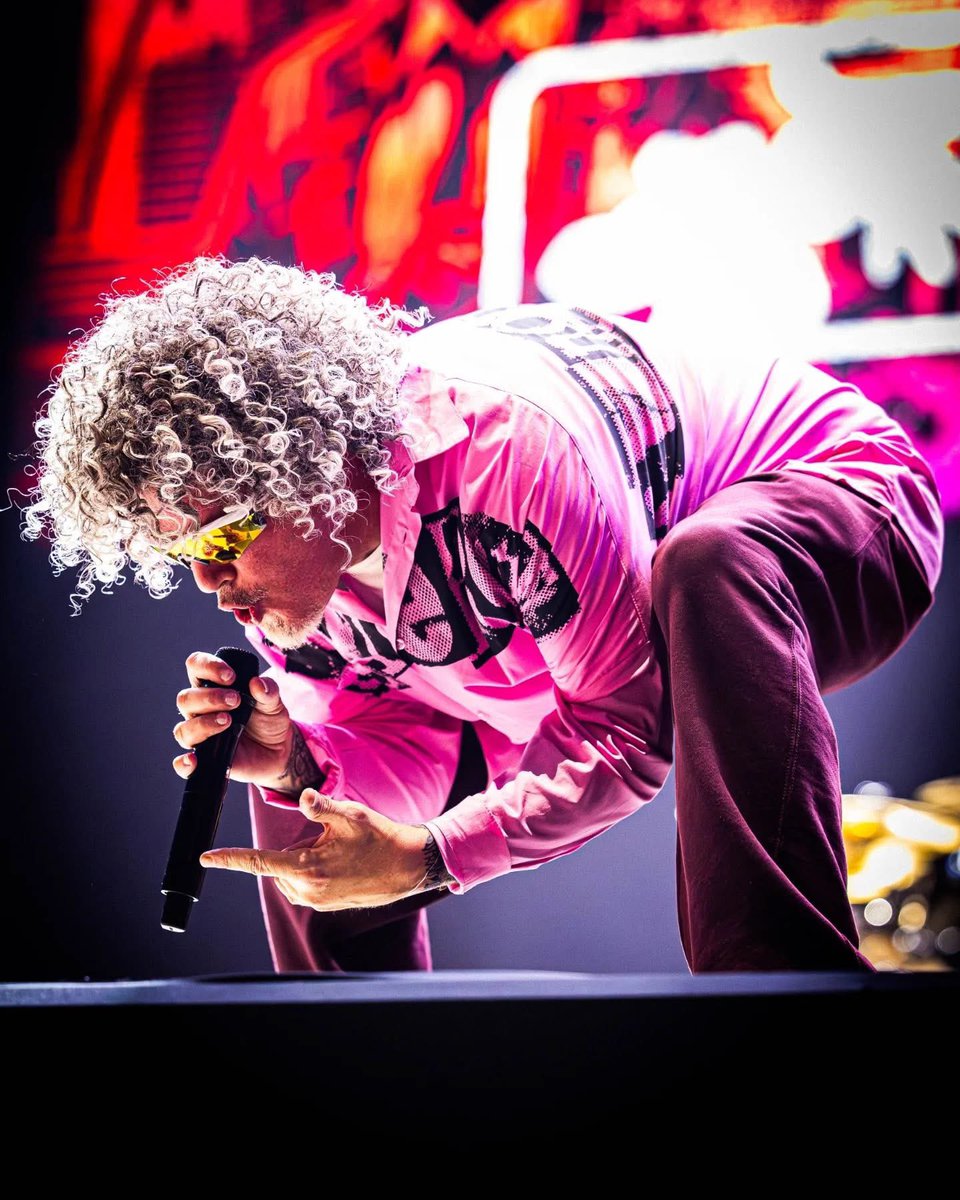 Cantor se apresenta com roupa colorida e microfone.