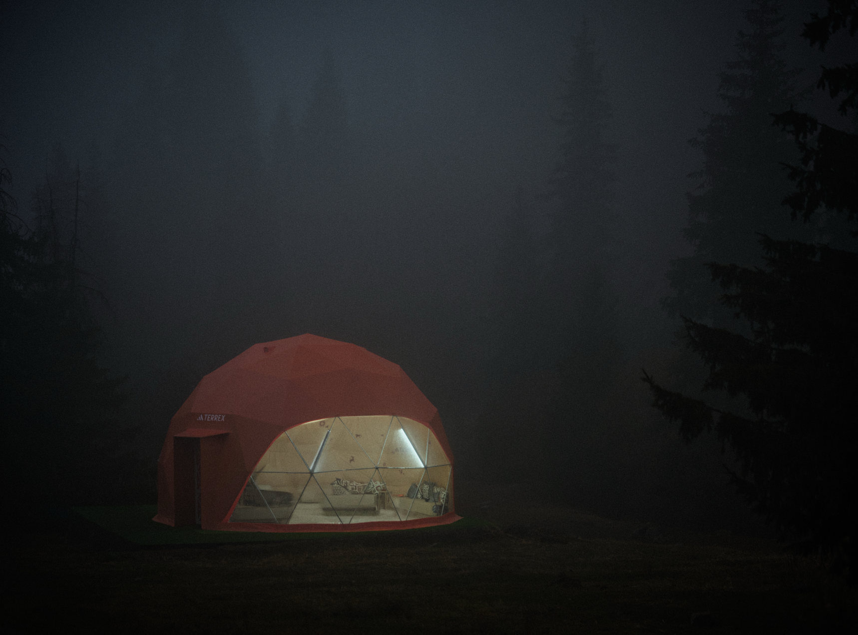 Cúpula geodésica em floresta nebulosa à noite.
