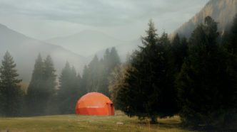 Tenda geodésica laranja em floresta nebulosa