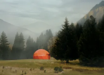 Tenda geodésica laranja em floresta nebulosa
