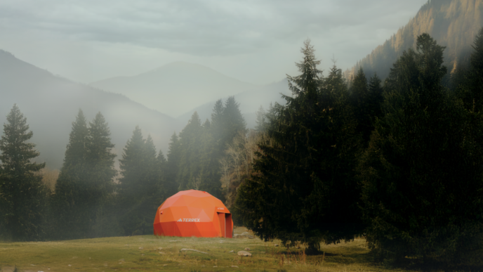 Tenda geodésica laranja em floresta nebulosa