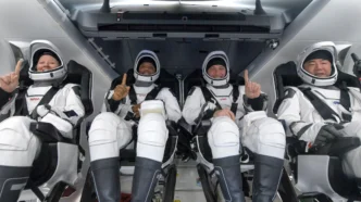 Quatro astronautas em trajes espaciais sorrindo na nave.