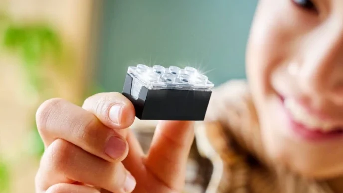 Criança segurando peça de construção preta brilhante.