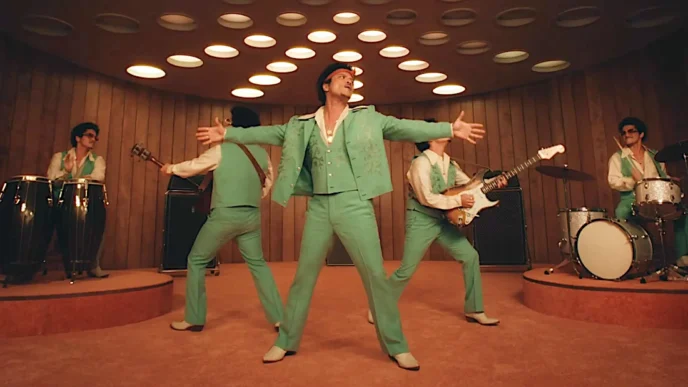 Banda tocando em palco, vestida de verde.