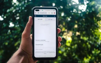 AI-SPM. Smartphone exibindo site ChatGPT em ambiente externo.