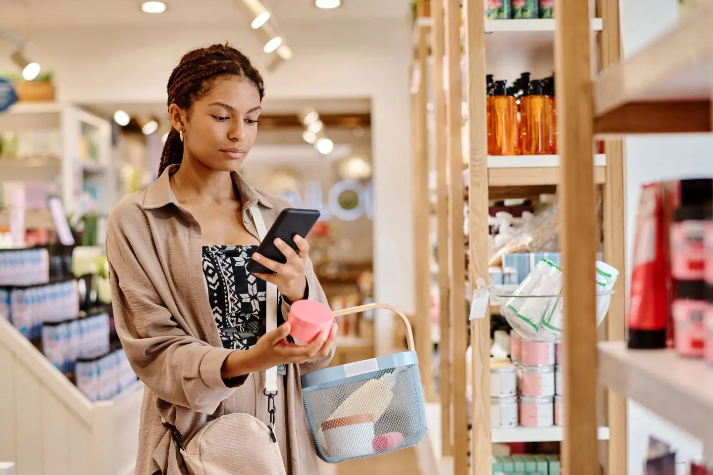NRF 2026. Mulher comprando cosméticos enquanto usa o celular.