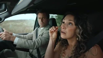 Mulher maquia-se enquanto passageiro dirige carro.