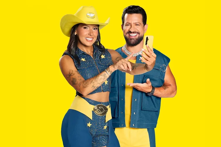 Duas pessoas sorrindo com smartphone, fundo amarelo.