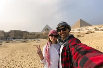 Casal tira selfie na frente das pirâmides do Egito.