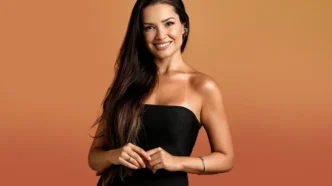 Mulher sorrindo com vestido preto e fundo laranja.