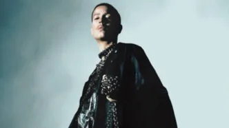 Pessoa em traje preto com colar na penumbra.