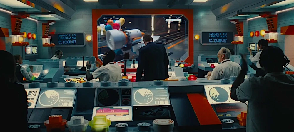 Sala de controle com cientistas assistindo tela grande.