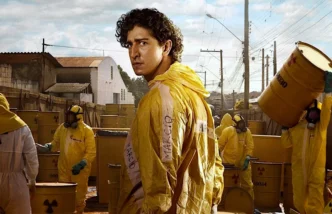 Homem em traje amarelo perto de tambores radioativos.