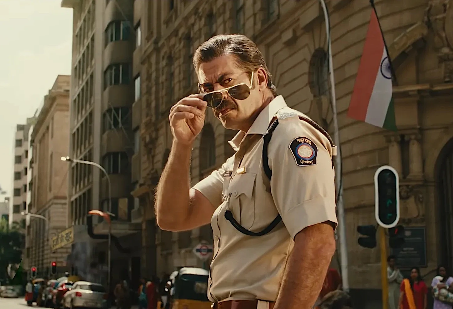 Policial com óculos escuros em rua movimentada.