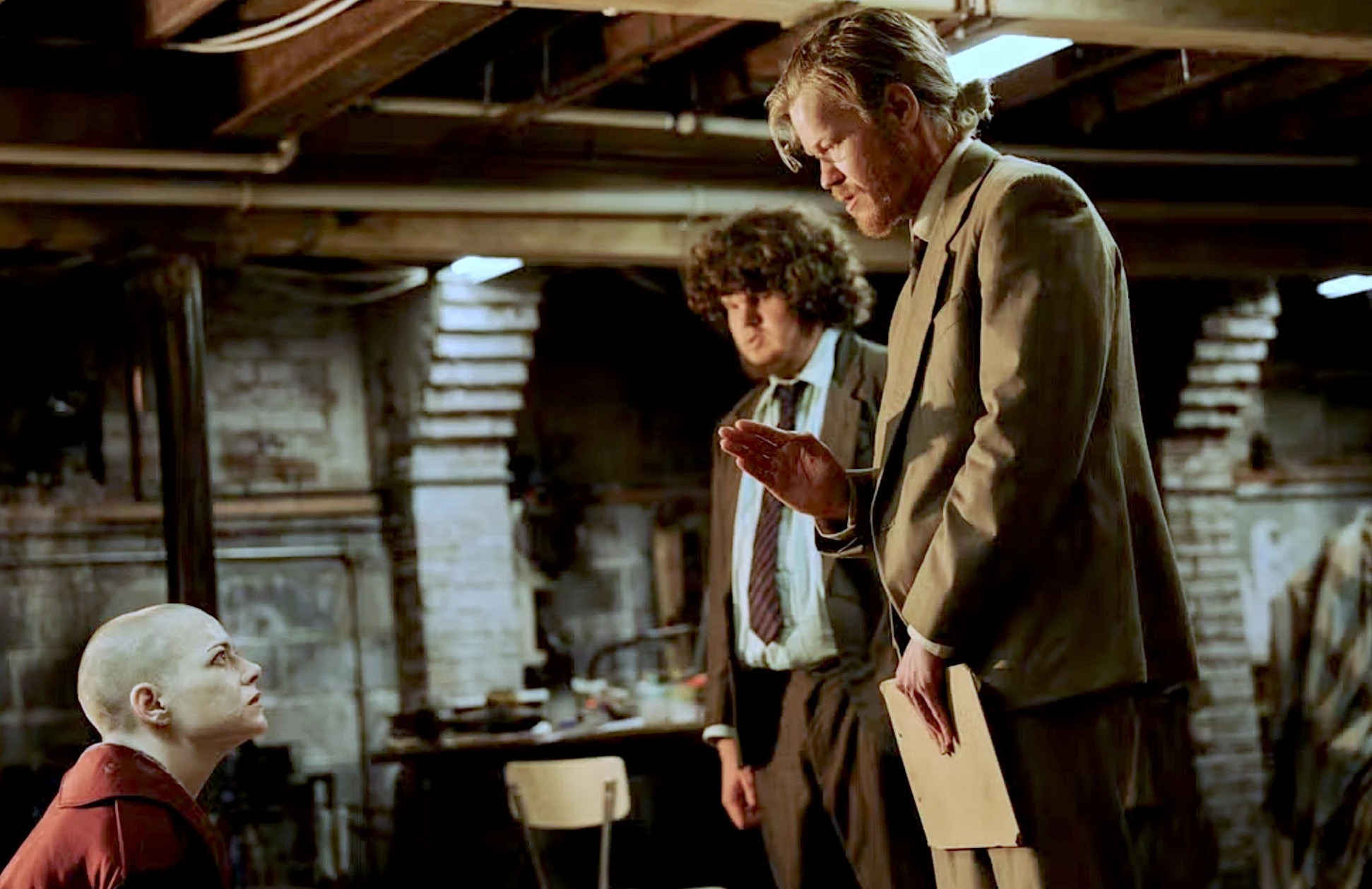 Homens discutem em porão escuro.