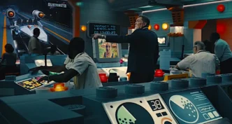 Homem apontando para tela em sala de controle.