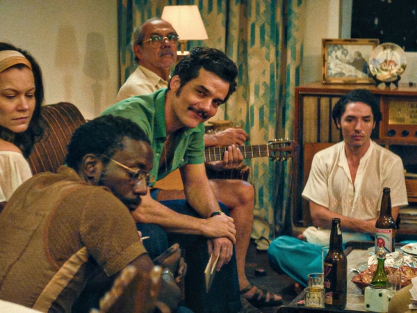 Grupo de amigos reunidos com violão e bebidas.