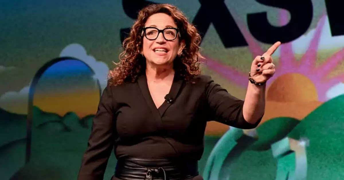 Mulher falando no palco, gesto com mão levantada.