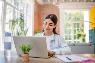 Mulher trabalhando no laptop em escritório iluminado