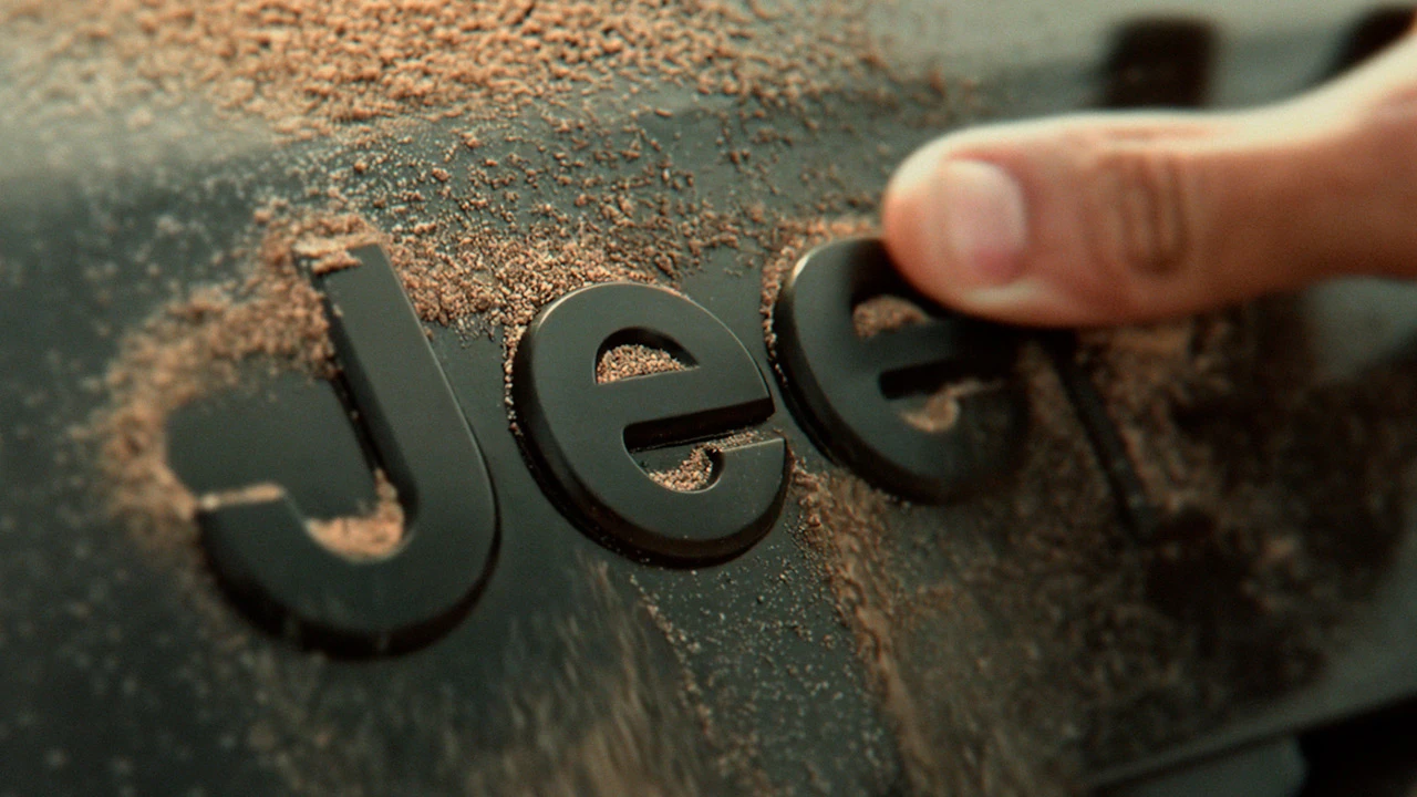 Logotipo Jeep coberto de poeira sendo limpo