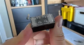 Peça transparente tipo LEGO segurada na mão