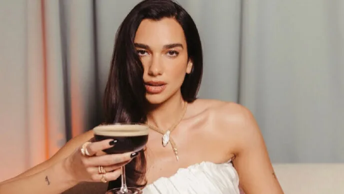 Mulher com vestido branco segurando coquetel escuro