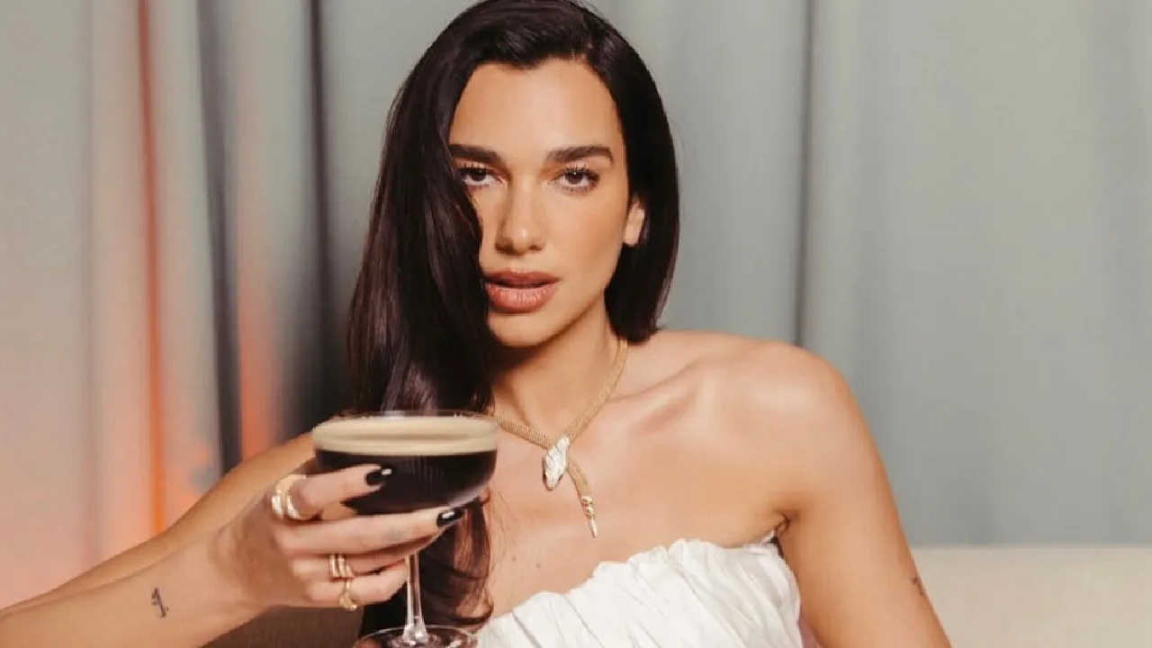 Mulher com vestido branco segurando coquetel escuro