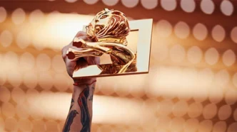 Mão segurando troféu dourado contra luzes desfocadas