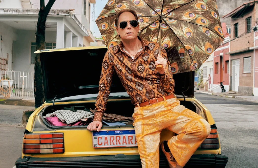 Homem com guarda-chuva estampado sentado em carro amarelo