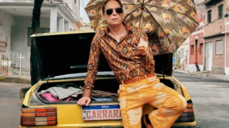 Homem com guarda-chuva estampado sentado em carro amarelo