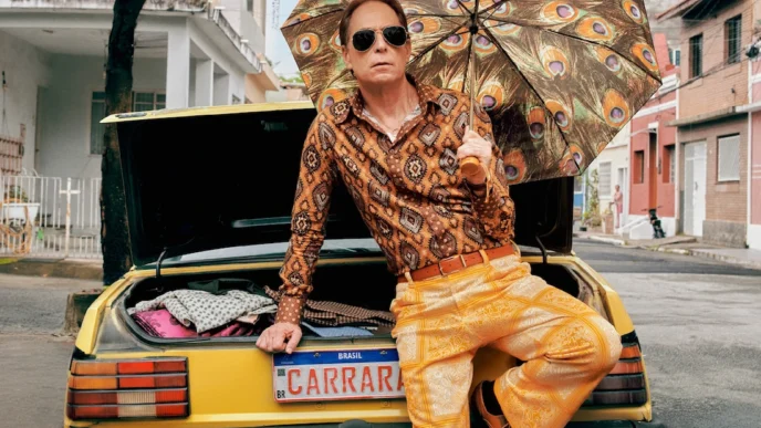 Homem com guarda-chuva estampado sentado em carro amarelo
