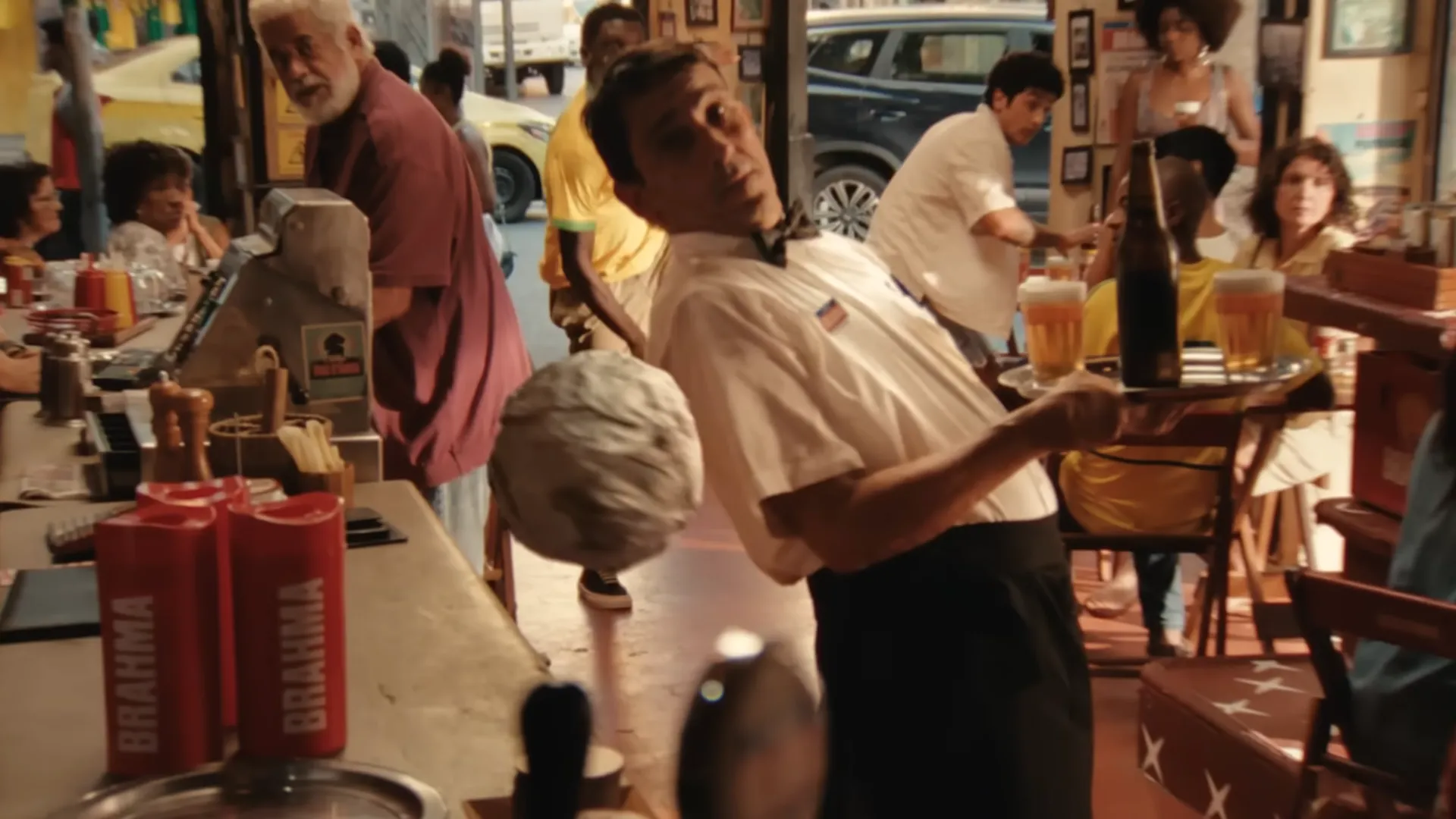 Garçom equilibra bandeja com cervejas em bar movimentado