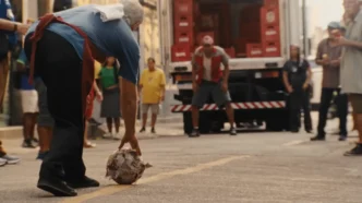 Homem pega bola de futebol na rua