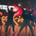 Grupo dançando em palco com luzes coloridas