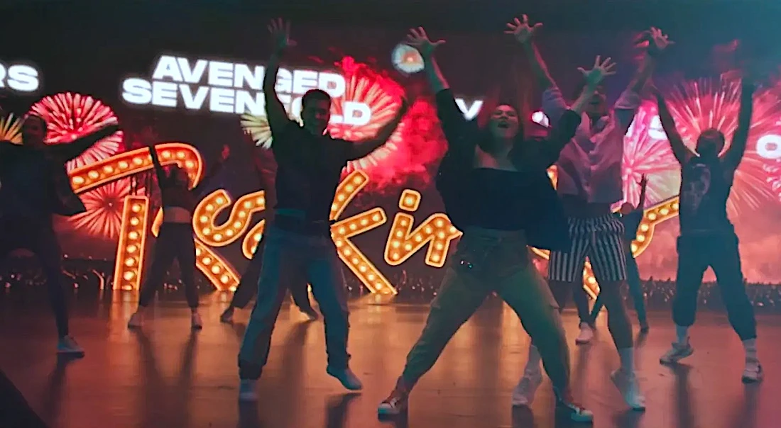 Grupo dançando em palco com luzes coloridas