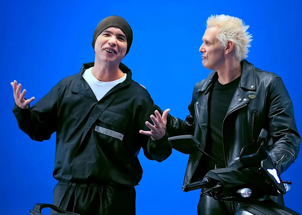 Dois homens ao lado de motocicleta fundo azul