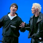 Dois homens ao lado de motocicleta fundo azul