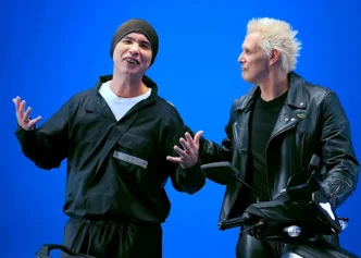 Dois homens ao lado de motocicleta fundo azul