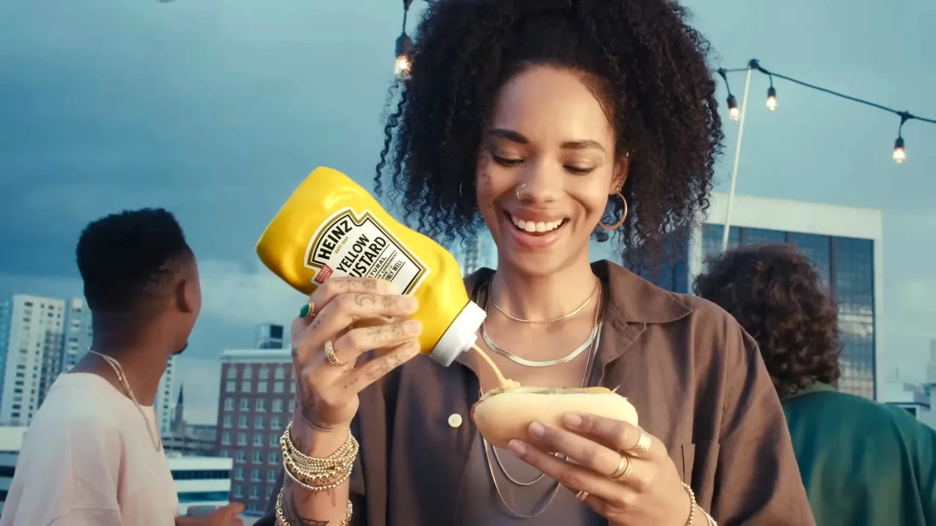 Mulher colocando mostarda Heinz em cachorro-quente