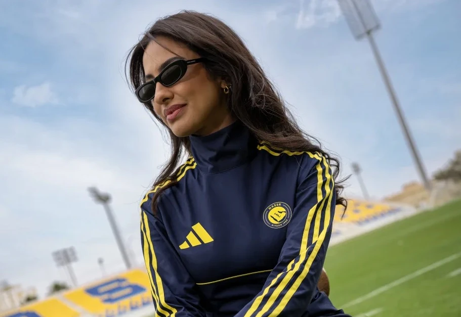 Mulher de óculos escuros em estádio de futebol