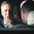 Homem idoso de terno conversando no carro