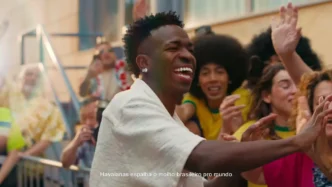 Homem sorrindo cumprimenta fãs em rua animada